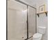 Bathroom showcasing a glass shower door, white tiles, and wooden shelf above the toilet at 613 Harrington Hls, Decatur, GA 30032