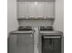 Laundry room featuring gray cabinets above side-by-side stainless steel washer and dryer at 613 Harrington Hls, Decatur, GA 30032