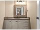 Bathroom vanity with granite counters, framed mirror, vanity cabinets and drawers, and dark hardware at 55 Moray Pl, Covington, GA 30014