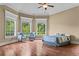 Bedroom featuring hardwood floors, a tray ceiling, two chairs, and three large windows at 55 Moray Pl, Covington, GA 30014
