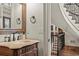 Elegant powder room featuring an ornate mirror, wood vanity, and decorative fixtures next to the stairway at 55 Moray Pl, Covington, GA 30014