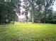 Expansive backyard featuring lush green grass, mature trees, and a view of the home and outdoor seating at 1642 Reflections Trl, Powder Springs, GA 30127