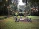 Relaxing backyard area with a fire pit and seating surrounded by mature trees and ambient string lights at 1642 Reflections Trl, Powder Springs, GA 30127