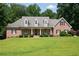 Charming brick home featuring a covered front porch, dormer windows, and manicured landscaping at 1642 Reflections Trl, Powder Springs, GA 30127