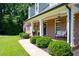 Inviting covered front porch with white columns, charming bench seating, and beautifully landscaped bushes at 1642 Reflections Trl, Powder Springs, GA 30127