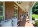 Charming covered front porch with classic brick flooring and inviting bench seating with decorative pillows at 1642 Reflections Trl, Powder Springs, GA 30127