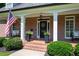 Inviting covered front porch with charming bench seating and beautifully landscaped bushes and planters at 1642 Reflections Trl, Powder Springs, GA 30127