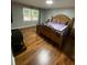 Comfortable bedroom featuring hardwood floors, a patterned bedspread, and natural light from a window at 284 Regal Dr, Lawrenceville, GA 30046