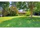 Beautifully landscaped front yard with lush green lawn and mature trees surrounding a charming brick home at 255 Jade Cove Dr, Roswell, GA 30075