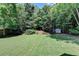 Well-maintained backyard with lush green grass, landscaping, and a storage shed surrounded by trees at 127 Bradshaw Park Dr, Woodstock, GA 30188