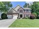 Charming two-story brick home with a well-manicured lawn, two-car garage, and beautifully landscaped front yard at 127 Bradshaw Park Dr, Woodstock, GA 30188