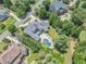 Aerial view showcases a lush property with in-ground pool, well-manicured lawn, mature trees, and spacious driveway at 3090 Creek Tree Lane, Cumming, GA 30041