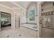 Bright bathroom featuring a glass enclosed shower and soaking tub with decorative window at 3090 Creek Tree Lane, Cumming, GA 30041
