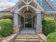 Stone steps lead to the clubhouse entrance with brick accents, gray pillars, and a covered entryway at 3090 Creek Tree Lane, Cumming, GA 30041