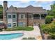 Rear exterior shot of clubhouse featuring a stone chimney, covered porch, pool area, and professional landscaping at 3090 Creek Tree Lane, Cumming, GA 30041