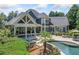 Charming home exterior featuring a covered porch, a stone patio with a fire pit, and a beautifully landscaped backyard pool area at 3090 Creek Tree Lane, Cumming, GA 30041