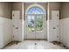 Grand foyer featuring light stone flooring, a large arched window door, and wainscoting detail at 3090 Creek Tree Lane, Cumming, GA 30041