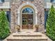 Detailed view of the front entrance with stone steps, decorative flower pots, and an arched doorway at 3090 Creek Tree Lane, Cumming, GA 30041