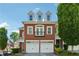 Charming brick townhome with a two-car garage and dormer windows under a clear blue sky at 11715 Dancliff Trce, Alpharetta, GA 30009