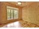 Bedroom with hardwood floors, large window overlooking green landscape, and ceiling fan for optimal comfort at 257 Martin Ln, Canton, GA 30114
