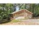 View of the detached two-car garage featuring stone siding, surrounded by trees at 257 Martin Ln, Canton, GA 30114