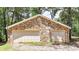 Detached garage featuring stone siding and two garage doors, surrounded by lush trees at 257 Martin Ln, Canton, GA 30114