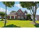 Beautiful brick home with a lush green lawn and mature trees providing shade and curb appeal at 7160 Fawn Lake Dr, Alpharetta, GA 30005