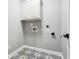 Laundry room with patterned tile floor and overhead storage at 7160 Fawn Lake Dr, Alpharetta, GA 30005