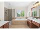 Bright bathroom featuring a shower, a soaking tub and a double vanity with wood cabinets and a large window at 1215 Renaissance Se Ct, Mableton, GA 30126