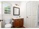 Powder room with window, wood cabinets and an adjacent door at 1215 Renaissance Se Ct, Mableton, GA 30126