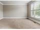 Neutral, empty carpeted bedroom with a large window offering view of the neighborhood at 2602 Alcovy Club Dr, Dacula, GA 30019