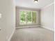 Bright, empty carpeted bedroom with a large window offering view of the neighborhood at 2602 Alcovy Club Dr, Dacula, GA 30019