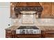 Exquisite detail in a kitchen's gas range and vent hood, showcasing custom cabinetry and granite countertops at 2602 Alcovy Club Dr, Dacula, GA 30019