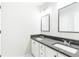 Bathroom featuring dual sinks, black marble countertop, white cabinetry, framed mirrors, and modern lighting at 8073 Ridge Vly, Woodstock, GA 30189