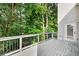 Back deck with iron railing, trees in background, outdoor lighting, and an access door to home at 8073 Ridge Vly, Woodstock, GA 30189