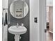 Stylish powder room featuring round mirror, pedestal sink, and dark accent wall at 217 Springs Xing, Canton, GA 30114