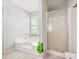 Bathroom with a large tub, glass shower, tiled floors and a window at 443 Rhett Dr, Loganville, GA 30052