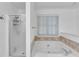 Bright bathroom showcasing a glass-enclosed shower and a separate soaking tub with tiled surround at 1481 Howard Way, Lawrenceville, GA 30043