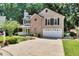 Traditional-style home with a brick facade, two-car garage, complemented by mature trees and a well-kept lawn at 1481 Howard Way, Lawrenceville, GA 30043