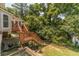 Backyard featuring a wooden deck with stairs leading to a lawn surrounded by mature trees at 4989 Woodfall Sw Dr, Lilburn, GA 30047