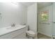 Bright bathroom featuring a white vanity, toilet, shower and a window that provides natural light at 4989 Woodfall Sw Dr, Lilburn, GA 30047