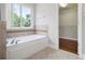 Bright bathroom features a soaking tub with tile surround and a view from the window at 5575 Julian Pl, Atlanta, GA 30342