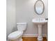Elegant half-bathroom with pedestal sink, oval mirror, and hardwood floors provides convenience at 5575 Julian Pl, Atlanta, GA 30342