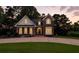 Inviting brick home with a manicured lawn, circular driveway, and warm lighting at dusk at 2845 Burgundy Dr, Cumming, GA 30041