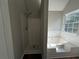 Bathroom featuring a separate soaking tub and walk-in shower, complemented by a bright window and wood look floors at 4189 Post Oak Grv, Atlanta, GA 30349
