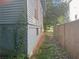 Side yard of a blue house with brick foundation, vine detailing, red-framed windows, and a wooden privacy fence at 1373 Lucile Sw Ave, Atlanta, GA 30310