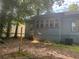 Exterior side view of the house with weathered blue siding, set in a lush, overgrown backyard at 1373 Lucile Sw Ave, Atlanta, GA 30310