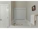 Bathroom featuring a jetted tub with tile surround, window, and a towel rack at 995 Lewis Ridge Cir, Lawrenceville, GA 30045