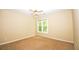 A cozy bedroom with neutral walls, carpet, a window offering view of outdoor greenery, and a ceiling fan at 1858 De Winton Pl, Lawrenceville, GA 30043
