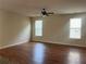Bright living room featuring hardwood flooring, a ceiling fan, and large windows offering natural light at 2423 Turnbury Glen Walk, Snellville, GA 30078